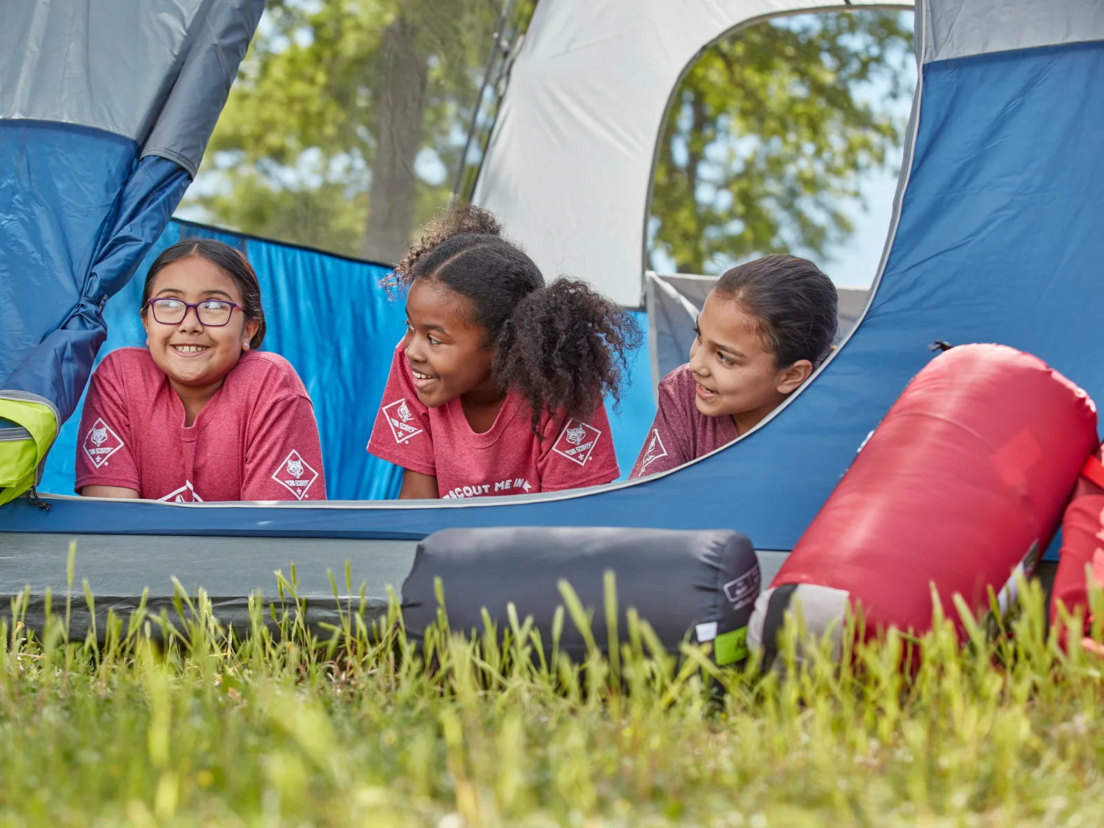Three Cub Scouts looking out from the door of their tent at a campout