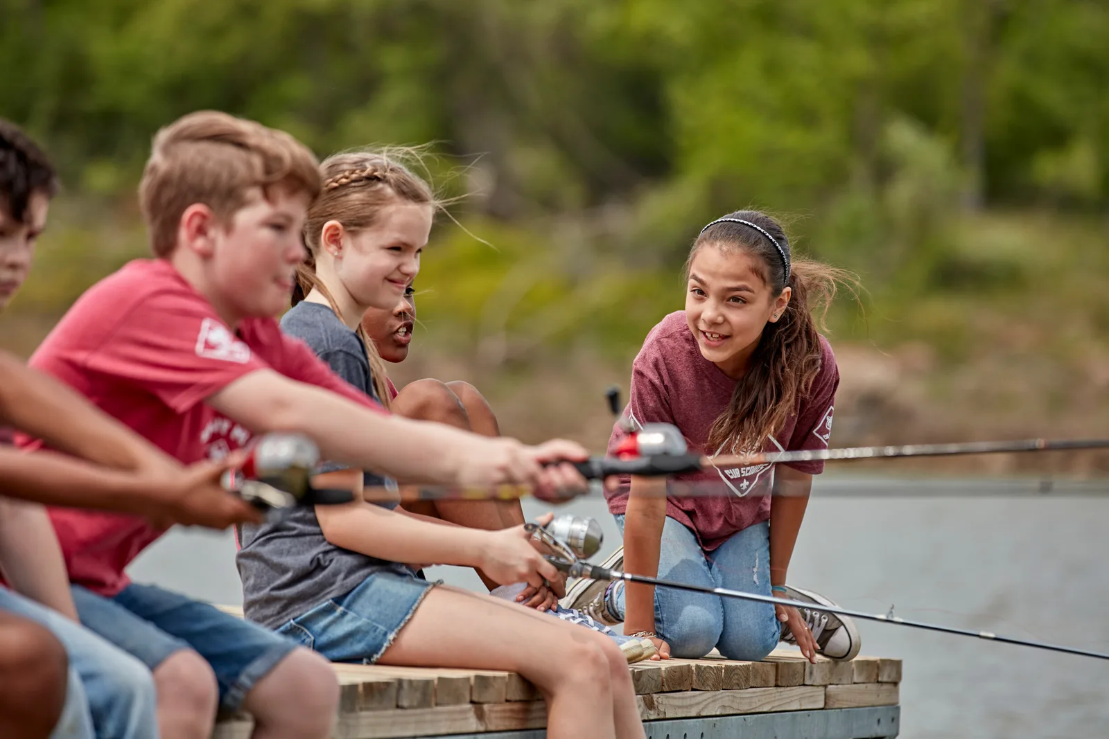 A row of Cub Scouts fishing from the end of a wooden dock