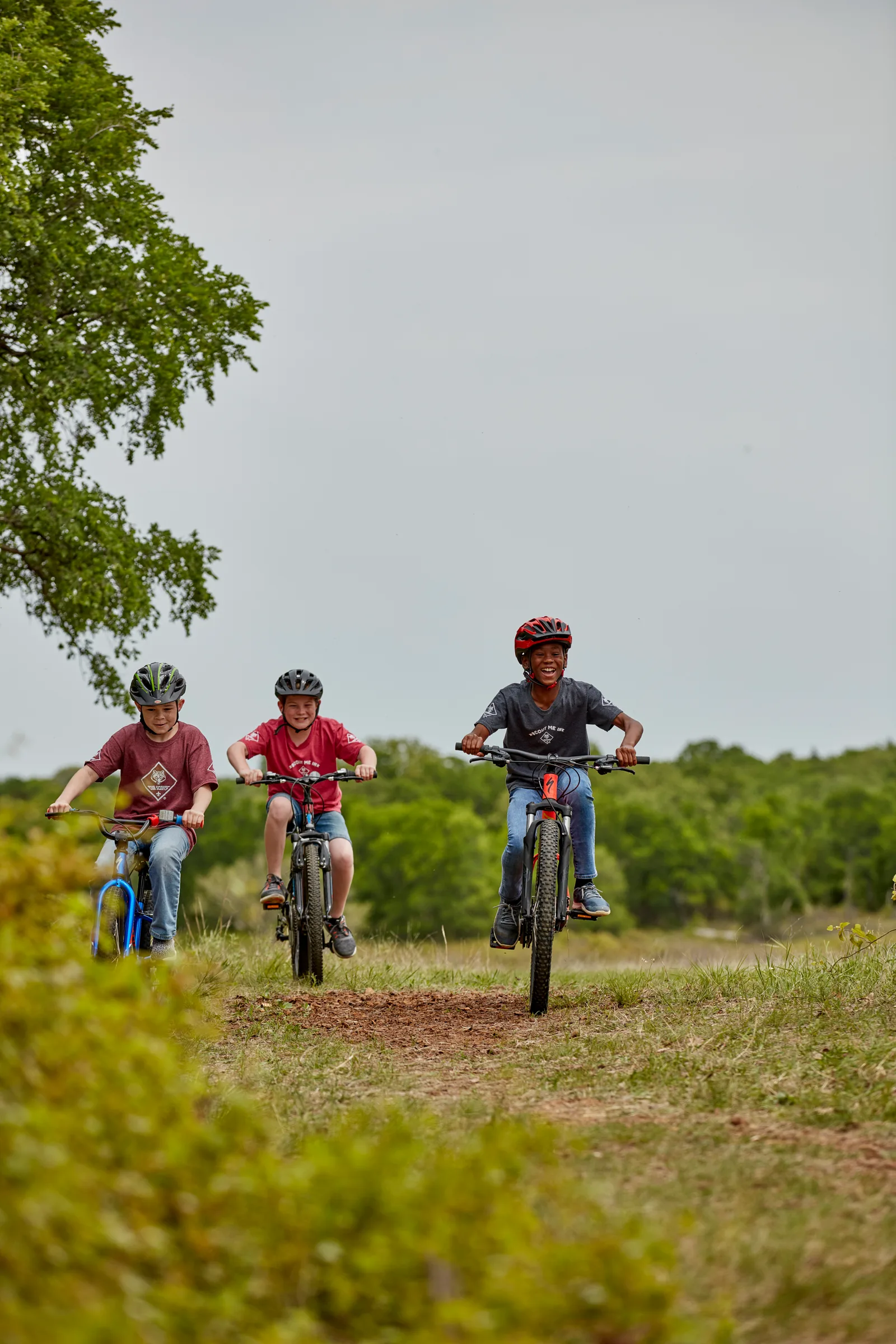 Three Cub Scouts riding bikes along a wooded trail