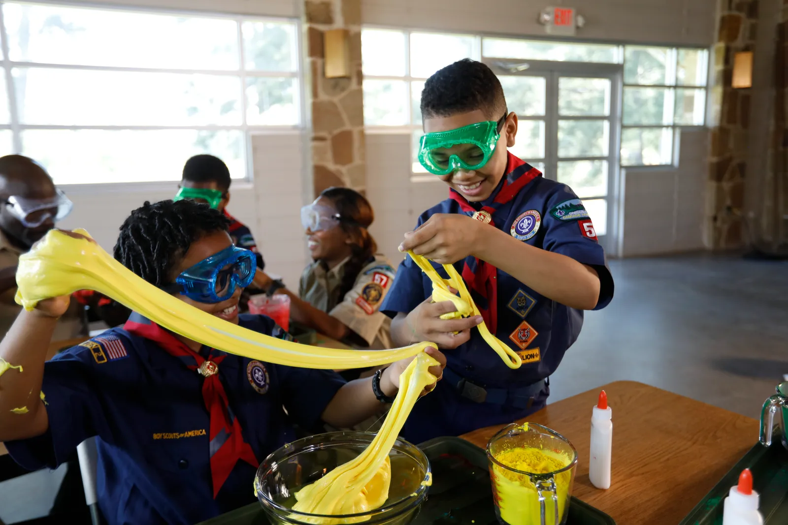 A Cub Scout stretching a handful of homemade slime during a den activity
