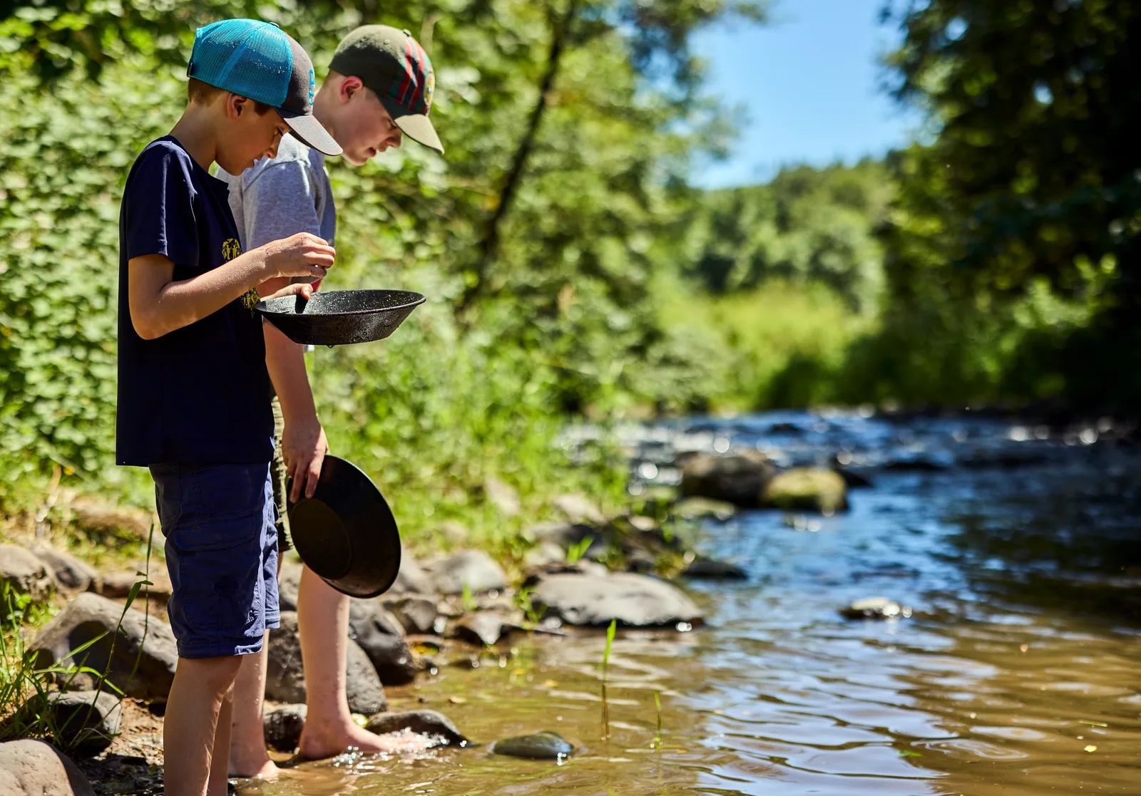 Two Cub Scouts panning for stones in a shallow creek