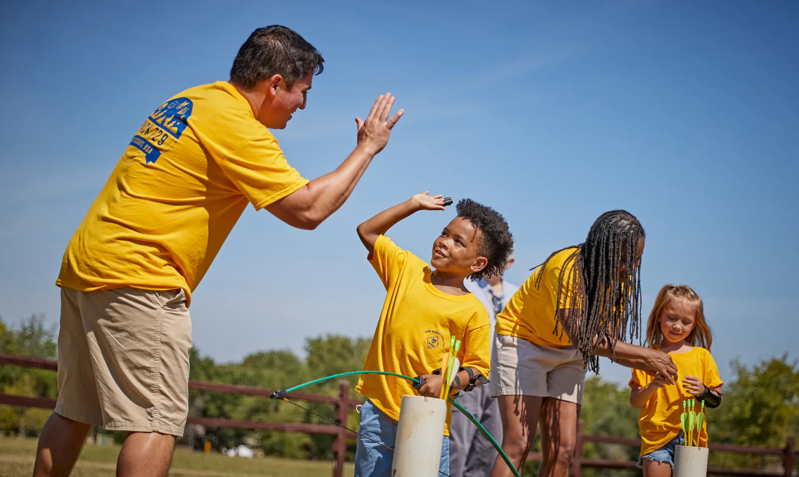 A leader high-fiving Cub Scouts after a rocket launch in an open field