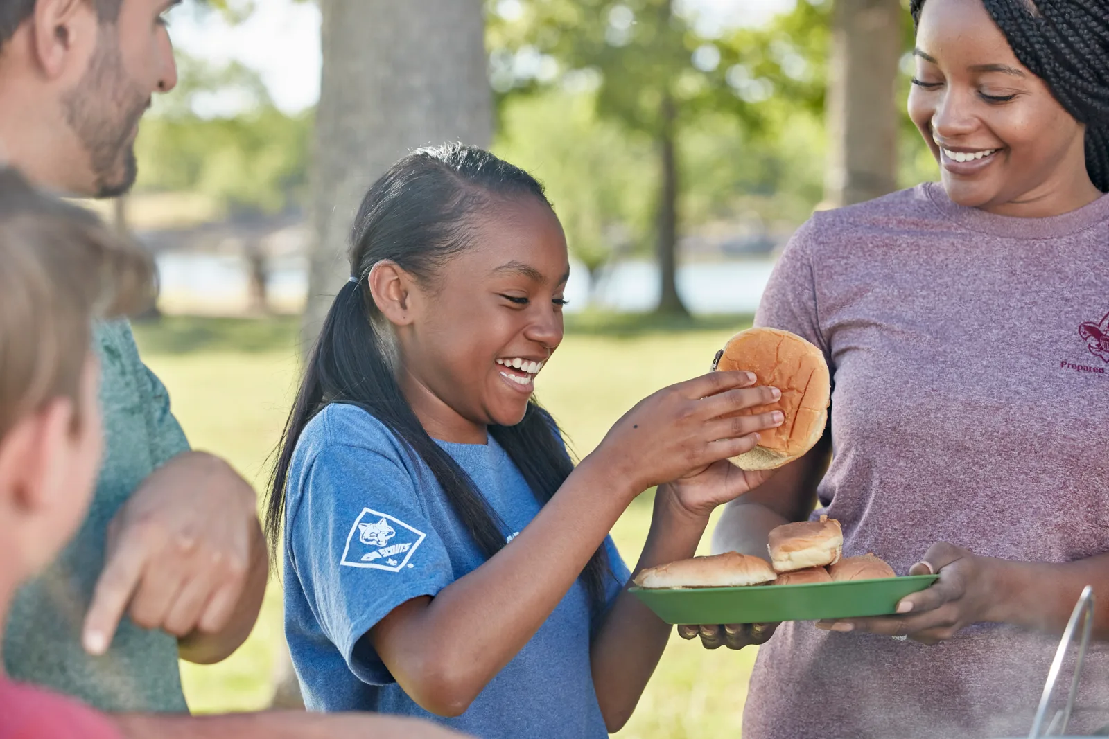 A Cub Scout laughing over a burger at a family cookout