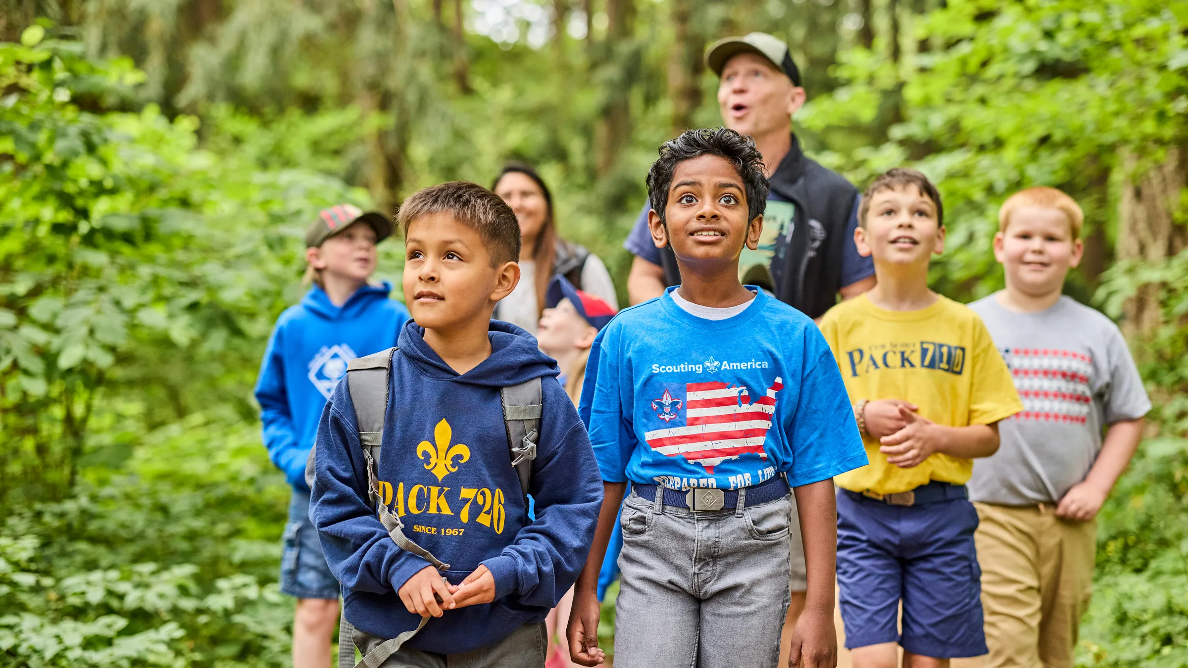 Cub Scouts and their families hiking a wooded trail together