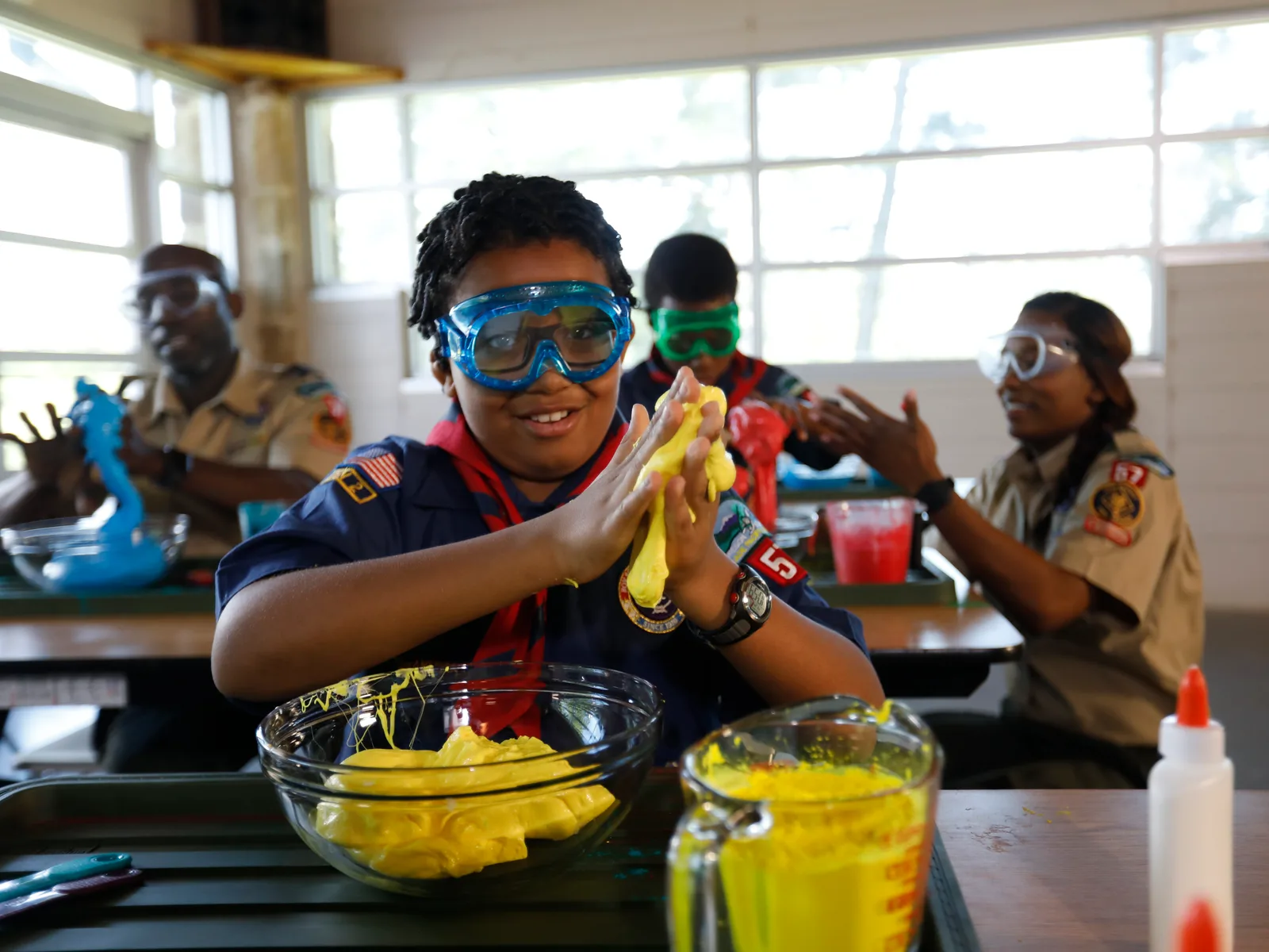 A den of uniformed Cub Scouts doing a science activity around a table